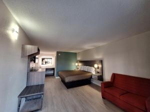 Roxboro经济汽车旅馆 - 罗克斯伯勒的酒店客房,配有一张床和一张红色的沙发