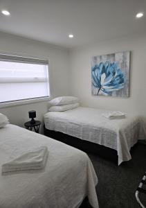 罗托鲁瓦Redwood Apartments的一间卧室设有两张床,墙上挂着一幅画