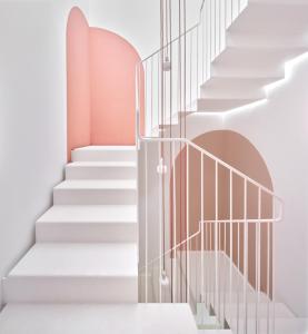 费雷列斯Ses Sucreres Small & Slow Hotel的楼梯有玻璃栏杆,白色的楼梯有粉红色的墙壁