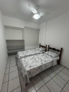 瓜拉派瑞Apartamento de 3 quartos na Praia da Fonte Guarapari的卧室内的两张床,配有吊扇