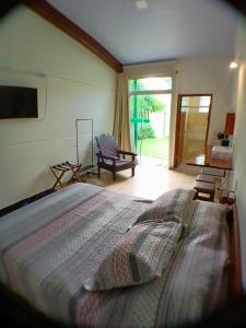 弗洛里亚诺波利斯Green Lodge Eco Life Hotel的一间卧室配有一张大床和一把椅子