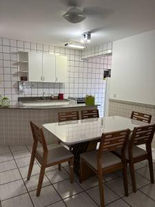 瓜拉派瑞Apartamento de 3 quartos na Praia da Fonte Guarapari的一间带桌椅的厨房和一间带白色橱柜的厨房