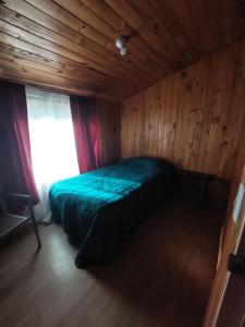 普孔Grandes cabañas的木制客房的一张床位,设有窗户