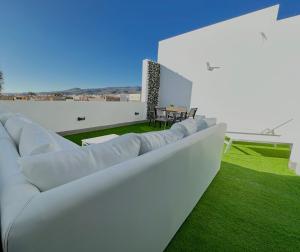 Castillo del RomeralSuites Verano Azul的客厅配有白色家具和绿色草地。