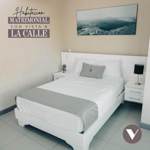 钦博特Hotel Viera Chimbote的白色卧室内的一张白色床,配有一个 ⁇ 色的标语