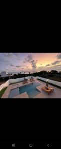 南蒂包PIPA Magnifique villa moderne en front de mer的一个带长椅和日落的大型游泳池