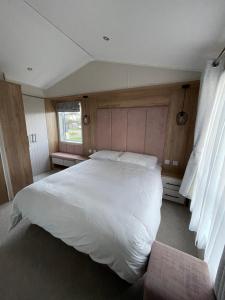 西拉尔沃思2-6 guests Holiday Chalet in Durdle Door的卧室设有一张白色大床和一扇窗户。