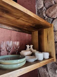 卢汉德库约Bendita Piedra Suites, Las Compuertas Lujan de Cuyo的木架上放有盘子和酒杯
