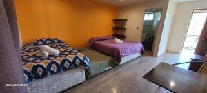 奥尔穆埃Habitaciones Tahiken的一间卧室设有两张床、一张桌子和一个窗口
