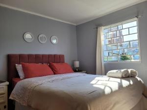 瓦尔帕莱索Cerca del Puerto y Plaza SotoMayor的一间卧室配有一张带红色枕头的床和一扇窗户