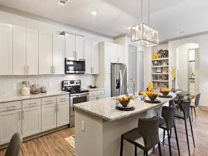亚特兰大Luxury 2br Apartment (Buckhead)的一间带白色橱柜的厨房和一个带椅子的厨房岛