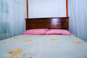 希克杜沃hikka T&O nature villa的一张带粉红色枕头和木制床头板的床