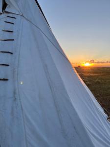 里弗顿JMA Tipi的白色帐篷的封闭式,背景是日落