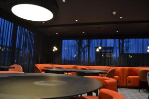 维佐拉提契诺TRIBE Milano Malpensa的用餐室设有橙色椅子、桌子和窗户。