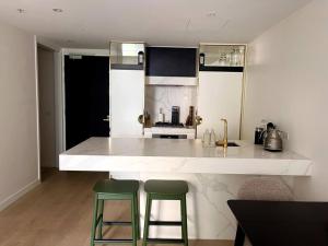 墨尔本Apartment in South Melbourne的厨房配有柜台和2张绿色酒吧凳