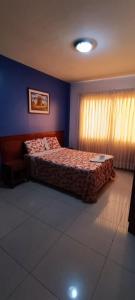 齐克拉约Hotel ESPLENDOR的一间卧室设有一张床和蓝色的墙壁