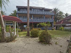 SolangonTropicasa Siquijor Seafront Guest House的棕榈树海滩上的一座大建筑