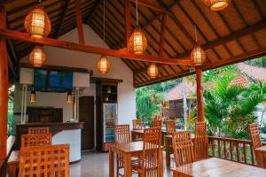 珀尼达岛Sawit Garden Cottages的餐厅设有木桌和椅子及灯
