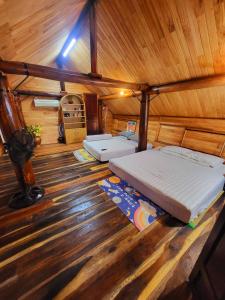 Buôn ÐũngNhà Sàn Bên Suối的小木屋内一间卧室,配有两张床