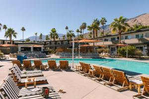 棕榈泉V Palm Springs的一个带游泳池、椅子和棕榈树的度假村