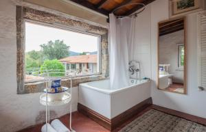 吉马良斯1720 Quinta da Cancela - Winery & Farmhouse的带浴缸的浴室和大窗户