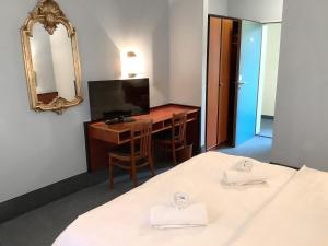 波恩Hotel Mozart Bonn的客房设有两张床、一张桌子和一面镜子。