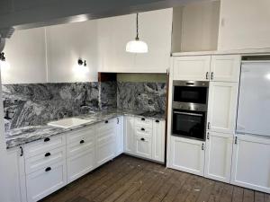 布里斯班Comfy Queenslander Cottage的厨房配有白色橱柜和白色家电