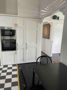 布里斯班Comfy Queenslander Cottage的厨房配有白色橱柜和 ⁇ 格地板