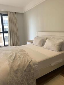内罗毕Apple Tree Apartment - 3beds -3Bedroom - 4 Washroom的白色的床、白色枕头和窗户