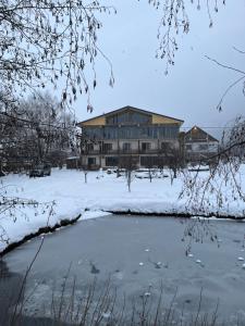 梅斯蒂亚Beko’s garden Inn的池塘旁的雪地建筑