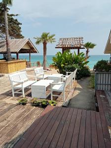 苏梅岛Amity Beach Resort的海滩上带白色椅子的木制甲板