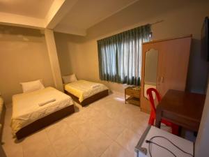 金边灰色旅馆的一间卧室配有两张床、一张桌子和一台电视。