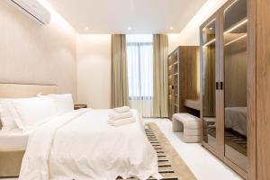 利雅德Amber Hospitality - Al Qairawan的卧室配有白色的床和步入式衣柜。