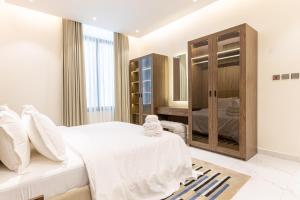 利雅德Amber Hospitality - Al Qairawan的卧室配有白色的床和木制橱柜。