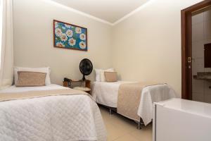 迪亚曼蒂纳POUSADA CAPIM LIMÃO的一间卧室设有两张床,墙上挂着一个时钟。