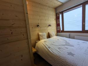 蒂涅Appartement au lac ski aux pieds的卧室配有木墙内的一张床
