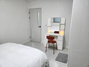 水原市Suwon station City House的白色卧室配有一张床和一张带镜子的书桌
