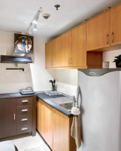 马尼拉Affordable Staycation Airbnb BGC的厨房配有木制橱柜和白色冰箱。