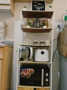马尼拉SERENDIPITY PLACE @CELANDINE的厨房架子配有烤面包机和微波炉