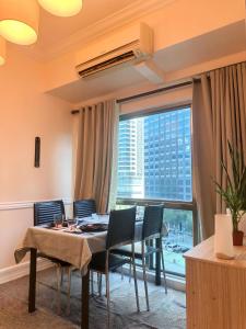 马尼拉Affordable Staycation Airbnb BGC的一间带桌椅和大窗户的用餐室