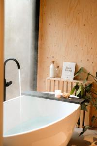 宁斯佩特Vague Luxurious Tiny House Luxe Wellness, Spa Bad,Beamer, Veluwe的带浴缸的浴室和木墙