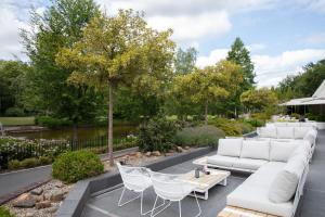 奥斯特韦克罗瑟普庄园的庭院配有白色的沙发、椅子和树木