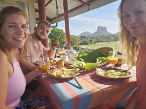 锡吉里亚Sigiriya Water Guest & View Point Restaurant的一群人坐在餐桌旁吃着食物