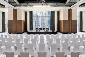 迪拜JW Marriott Hotel Marina的一间会议室,配有白色椅子和舞台