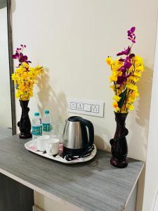 商沙巴Hotel Blue Petals的一张桌子,上面有两瓶花花和茶壶