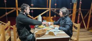 Cachorathe wooden house choquequirao的坐在餐桌旁吃食物的男人和女人
