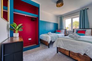 索利赫尔Large 4 bedroom house - driveway - close to NEC!的两张床位于带红色和蓝色墙壁的客房。