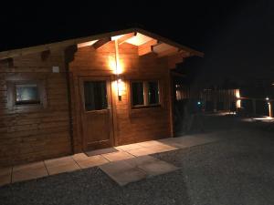 艾尔德里Lochinvar - Highland Log Cabin with Private Hot Tub的小木屋,晚上有门