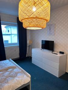 班贝格4rooms - Bamberger Gemütlichkeit的一间卧室配有一张床、一台电视和吊灯。