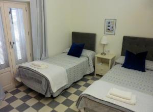 加的斯APARTAMENTO APODACA的一间卧室配有两张带蓝色枕头的床